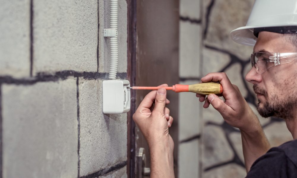 male electrician-technician, connects the equipment with a tool, the concept of the installer's work, space for text